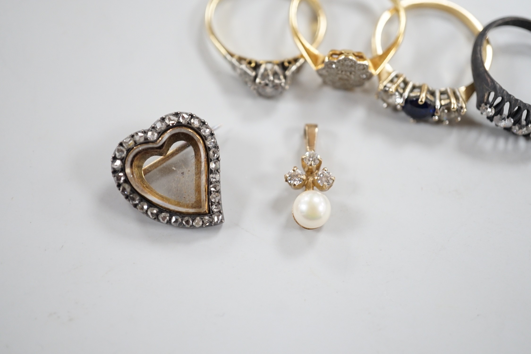 An 18ct, plat and single stone diamond ring, with diamond set shoulders, size O, a similar diamond cluster ring, size N, a blackened? 18ct gold and five stone diamond ring, a late Victorian diamond set heart shaped mourn